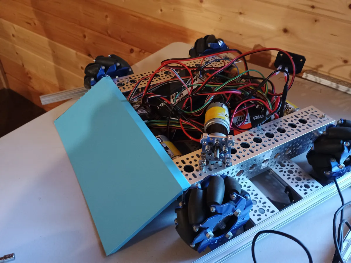 Second version of the intake ramp, printed in solid blue, leaning against the front of the robot