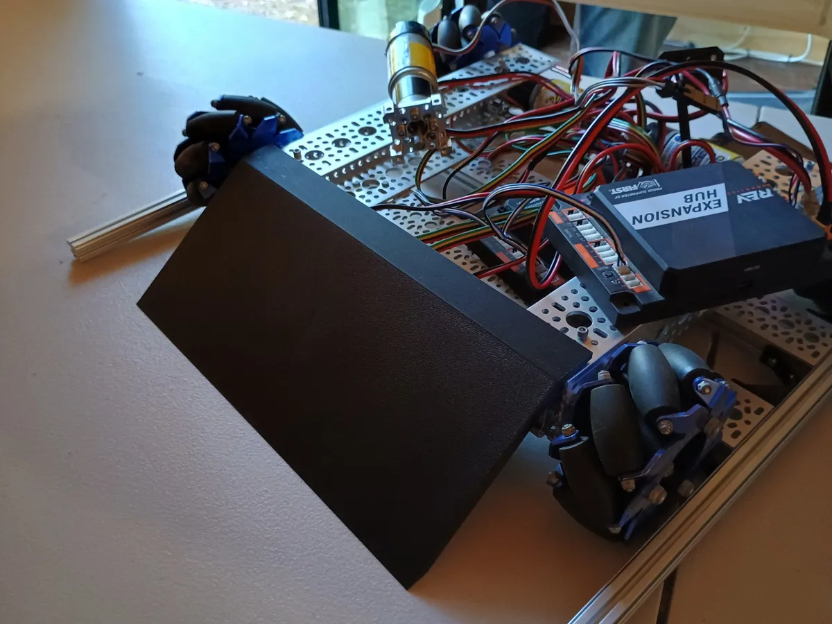 The black 3D-printed ramp mounted on the front of the robot, with the Expansion Hub and wiring behind it