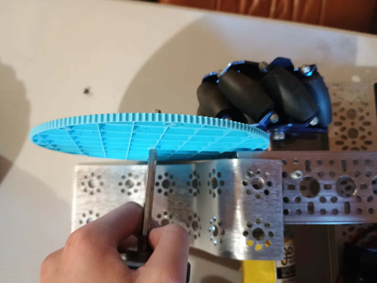 The light blue gear on a shaft, held next to the chassis to check the fit